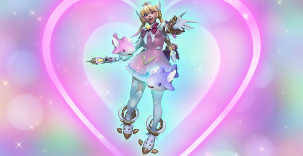 Juno in her Heart of Hope skin from Overwatch 2, wearing a pastel pink magical-girl outfit with playful shark-themed accessories, set against a glowing rainbow heart background with sparkles.