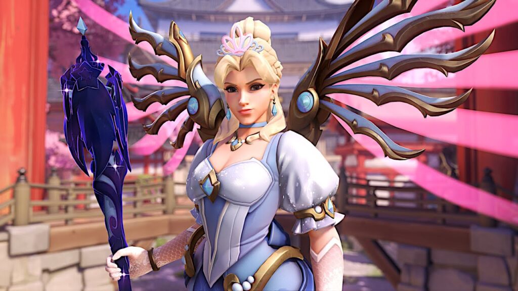 Royal Princess Mercy in a blue and white winged costume with golden accents holds a dark ornate staff