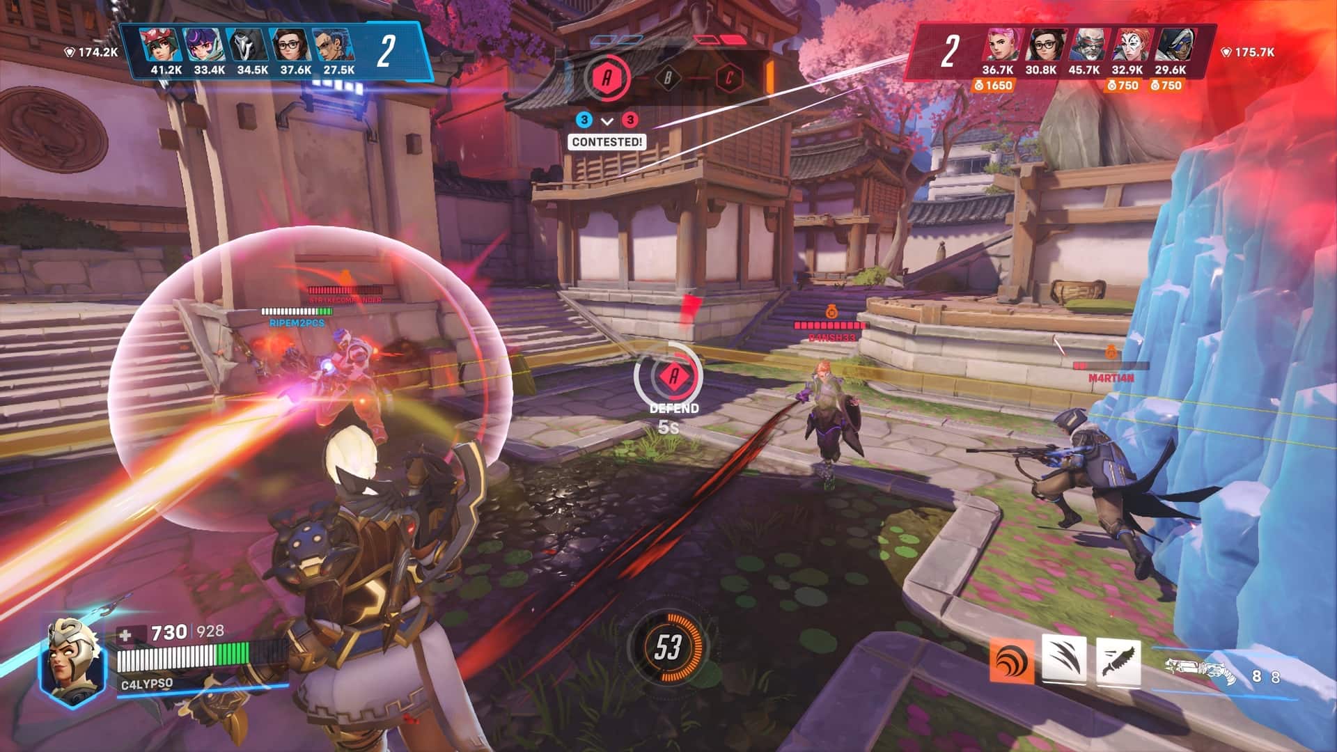 Screenshot from Overwatch 2 showing a tense battle scene. Characters are engaged in combat with shields and weapons